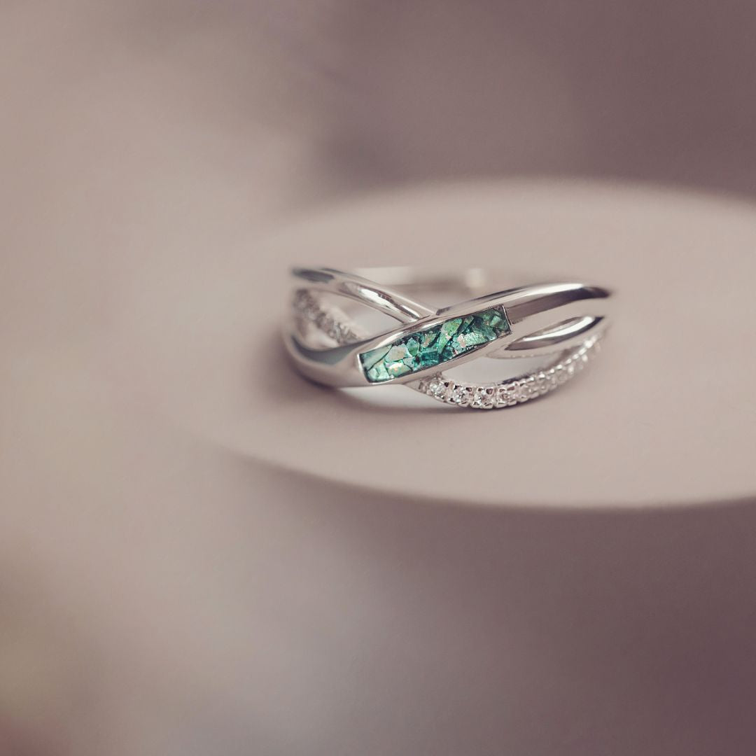 Silver ring with green gemstone on a blurred background