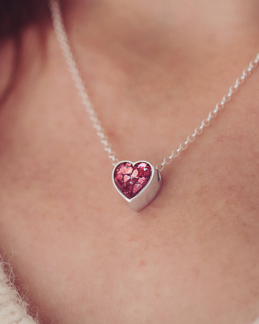 Sterling silver floating heart necklace, on a silver chain, being worn on a ladies necklace.