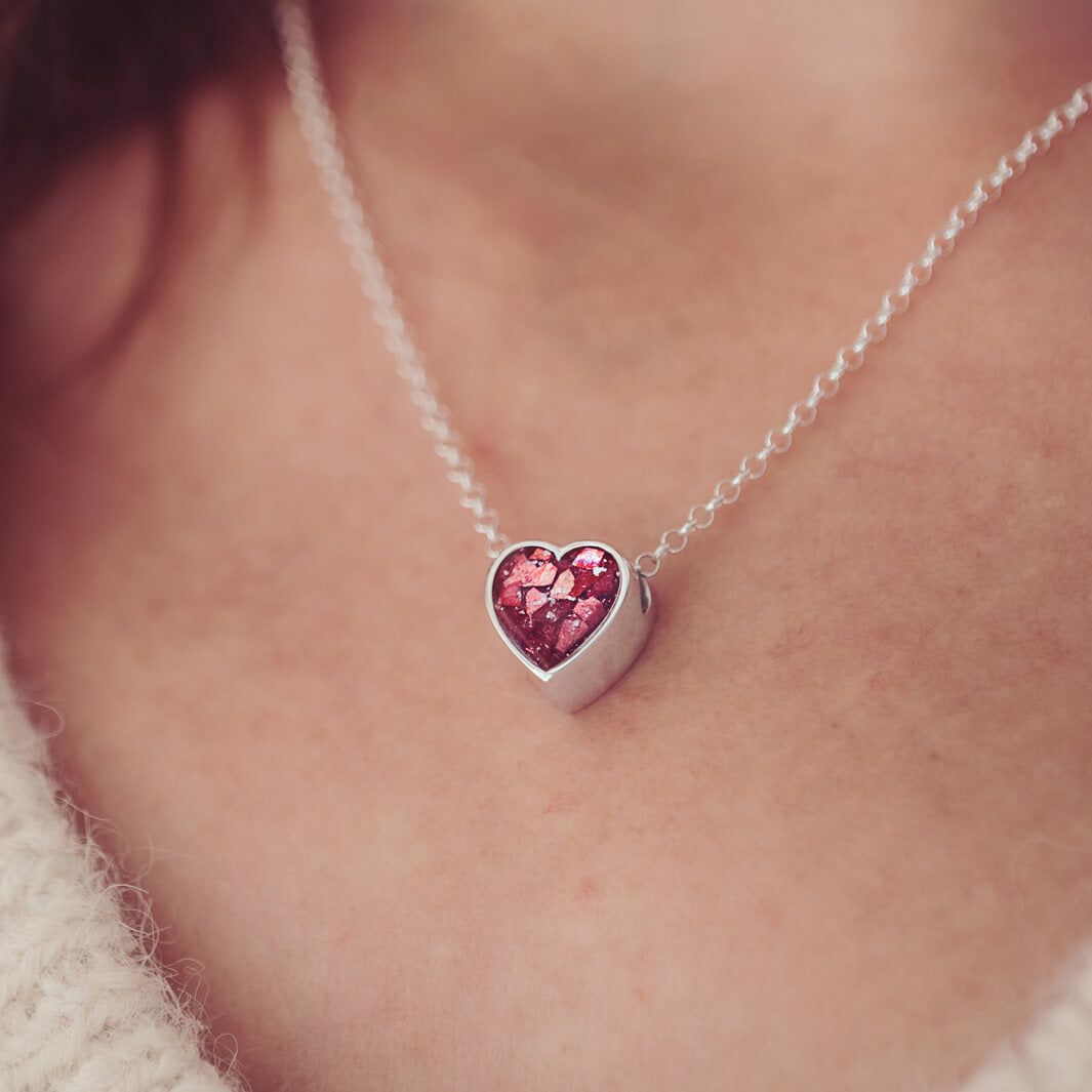 Sterling silver floating heart necklace, on a silver chain, being worn on a ladies necklace.