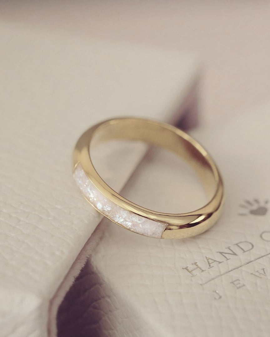 Gold ring with a white stone on a light background