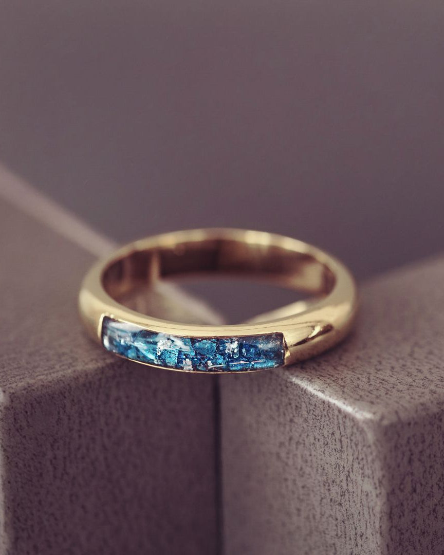 Gold ring with blue gemstones on a textured surface