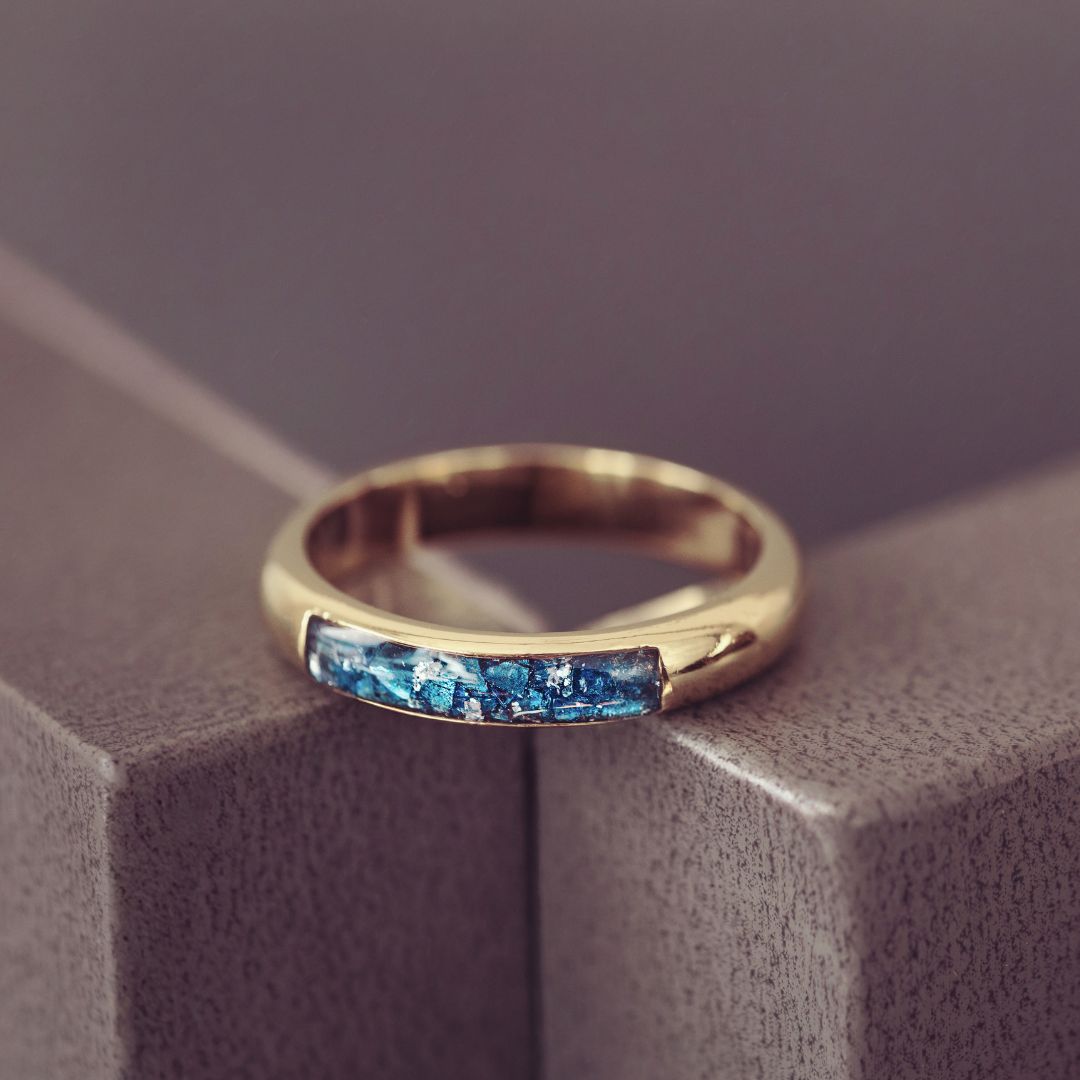 Gold ring with blue gemstones on a textured surface
