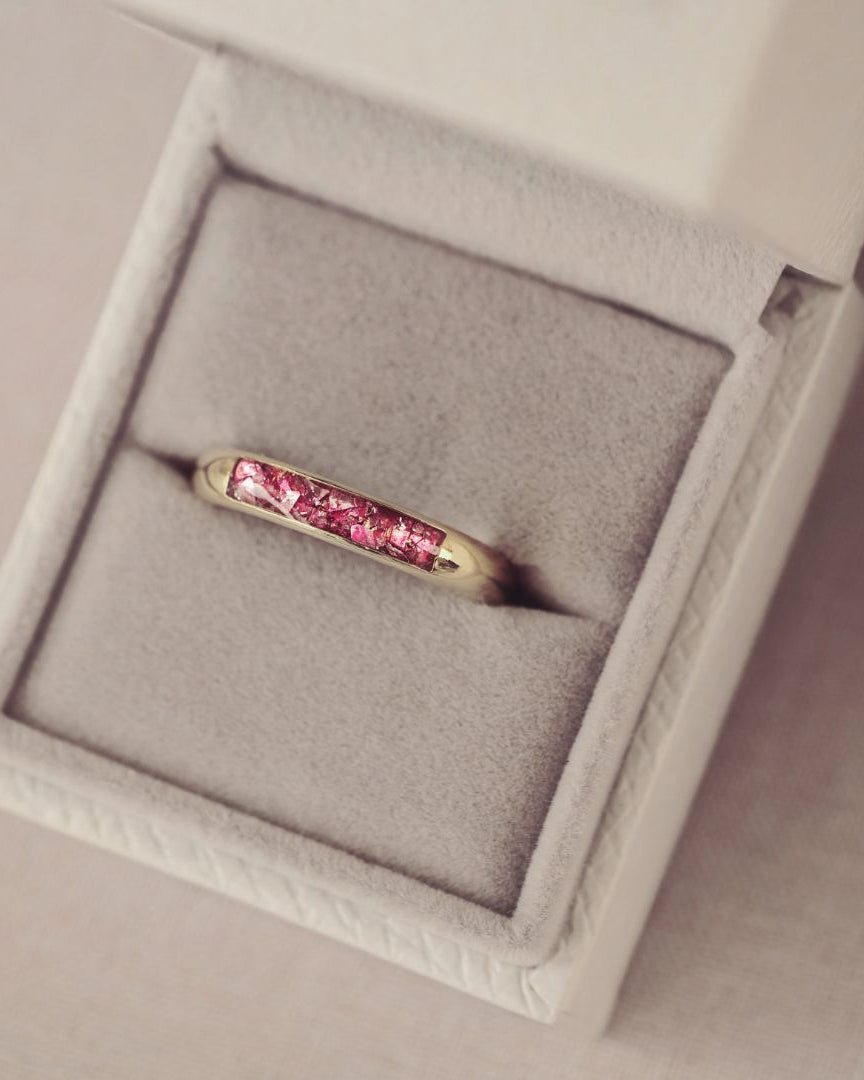 Gold ring with pink gemstones in a gray jewelry box