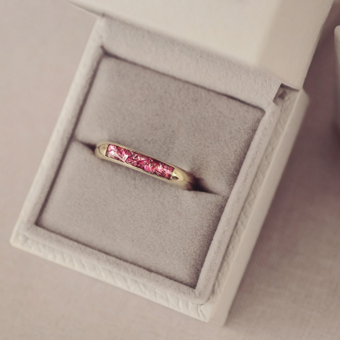 Gold ring with pink gemstones in a gray jewelry box
