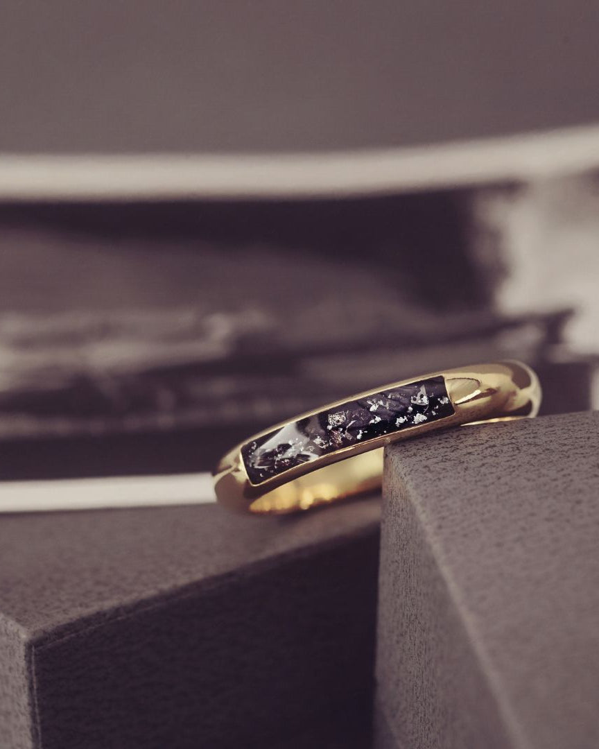Gold ring with embedded stones on a textured surface