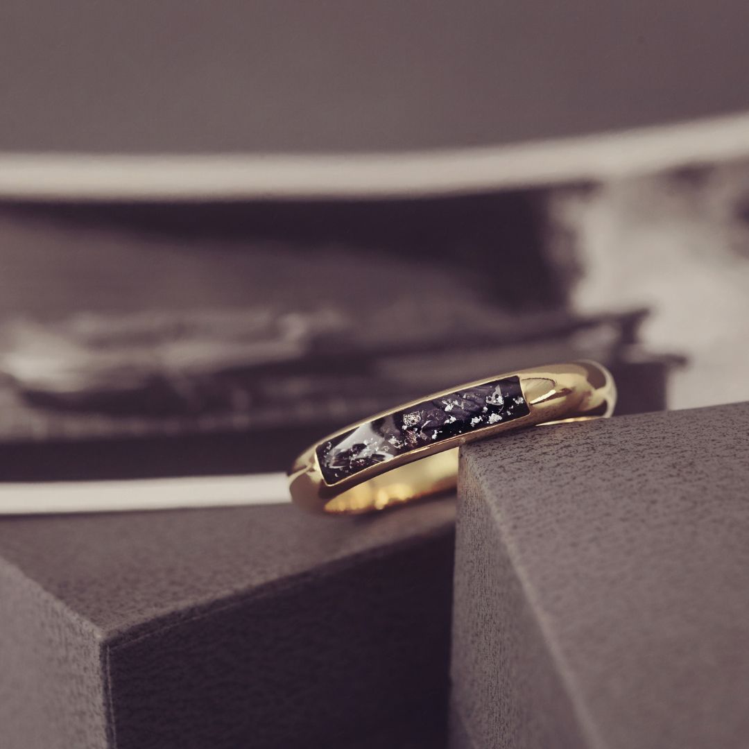 Gold ring with embedded stones on a textured surface