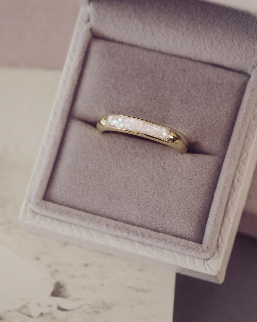 Gold ring with diamonds in a jewelry box on a neutral background