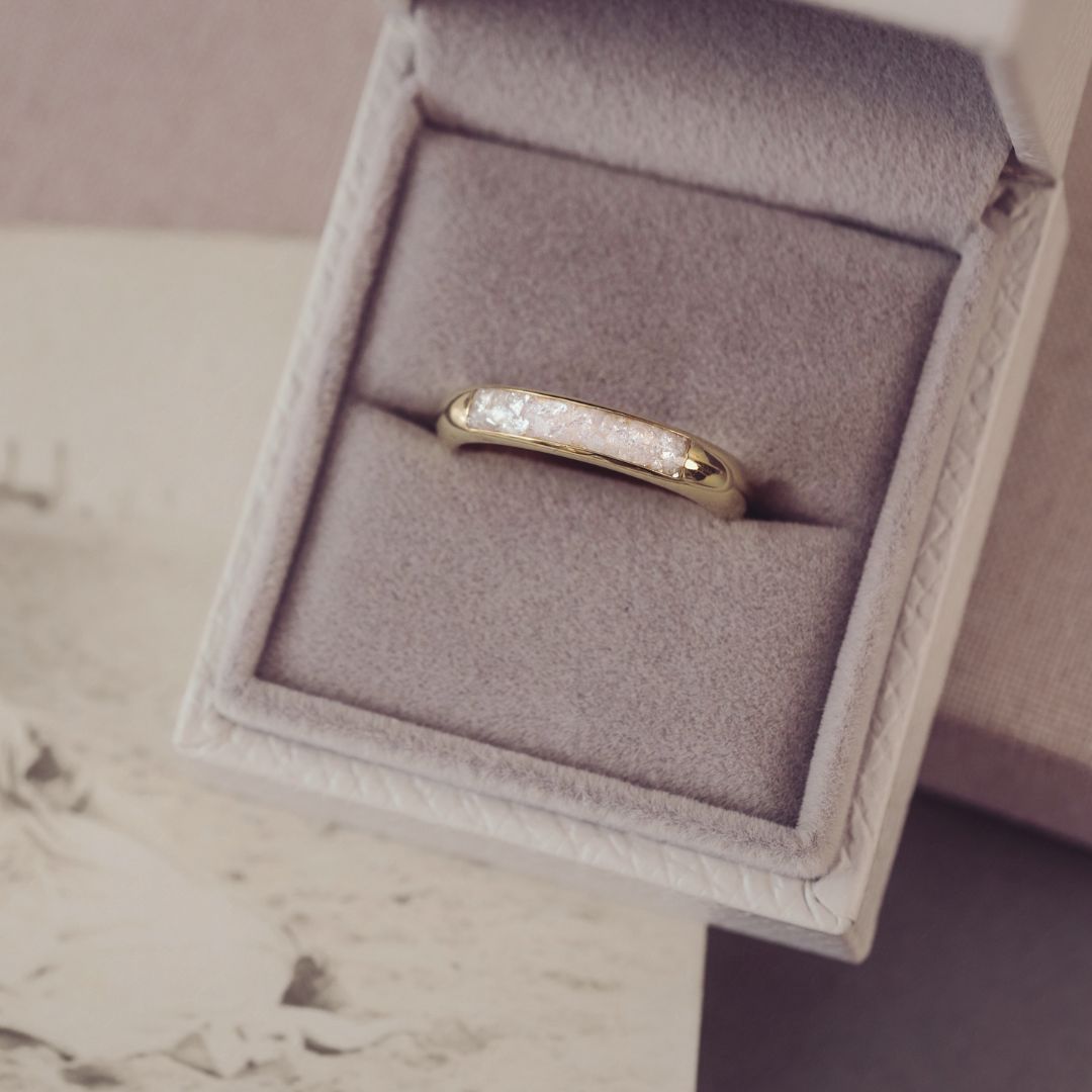 Gold ring with diamonds in a jewelry box on a neutral background