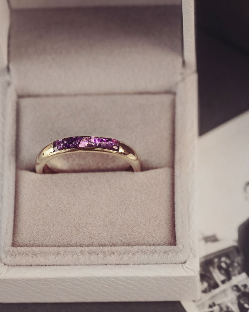 Gold ring with purple stones in a box next to an old photograph