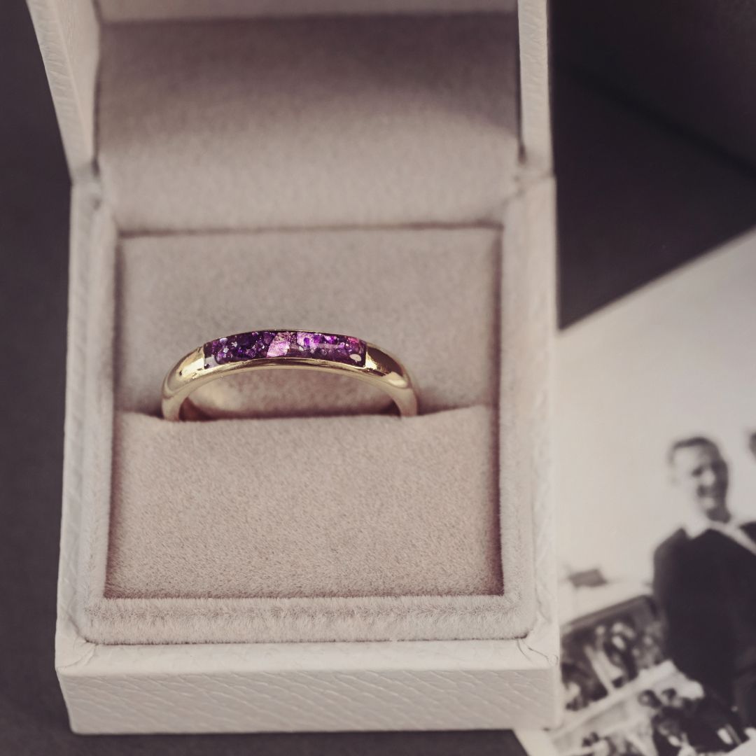 Gold ring with purple stones in a box next to an old photograph