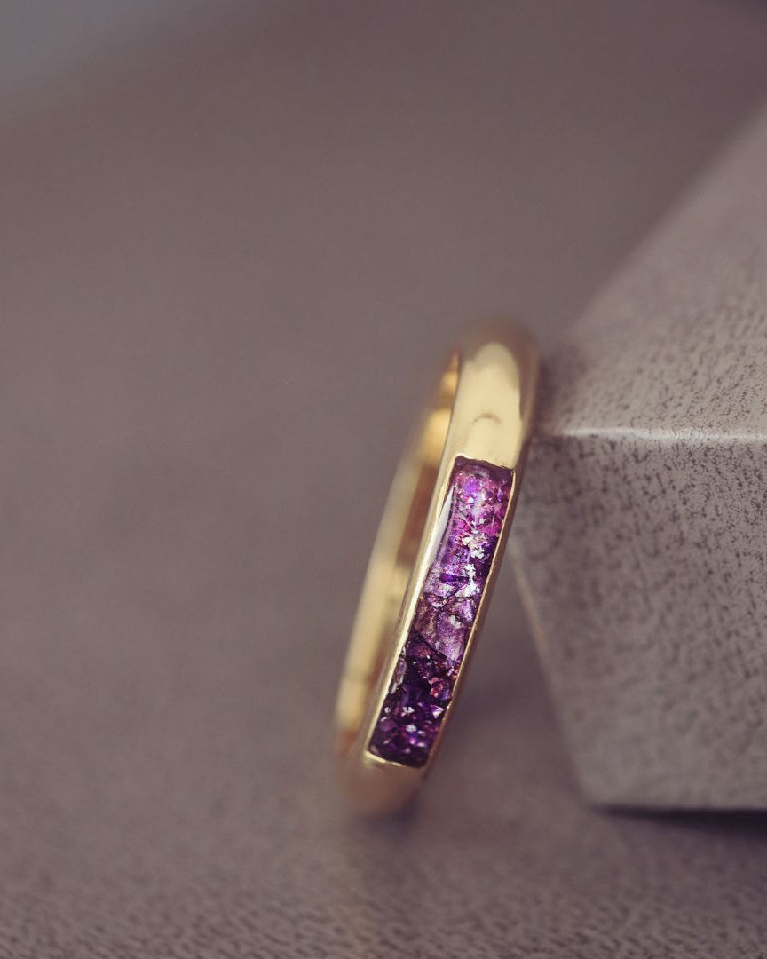 Gold ring with purple gemstones on a textured surface
