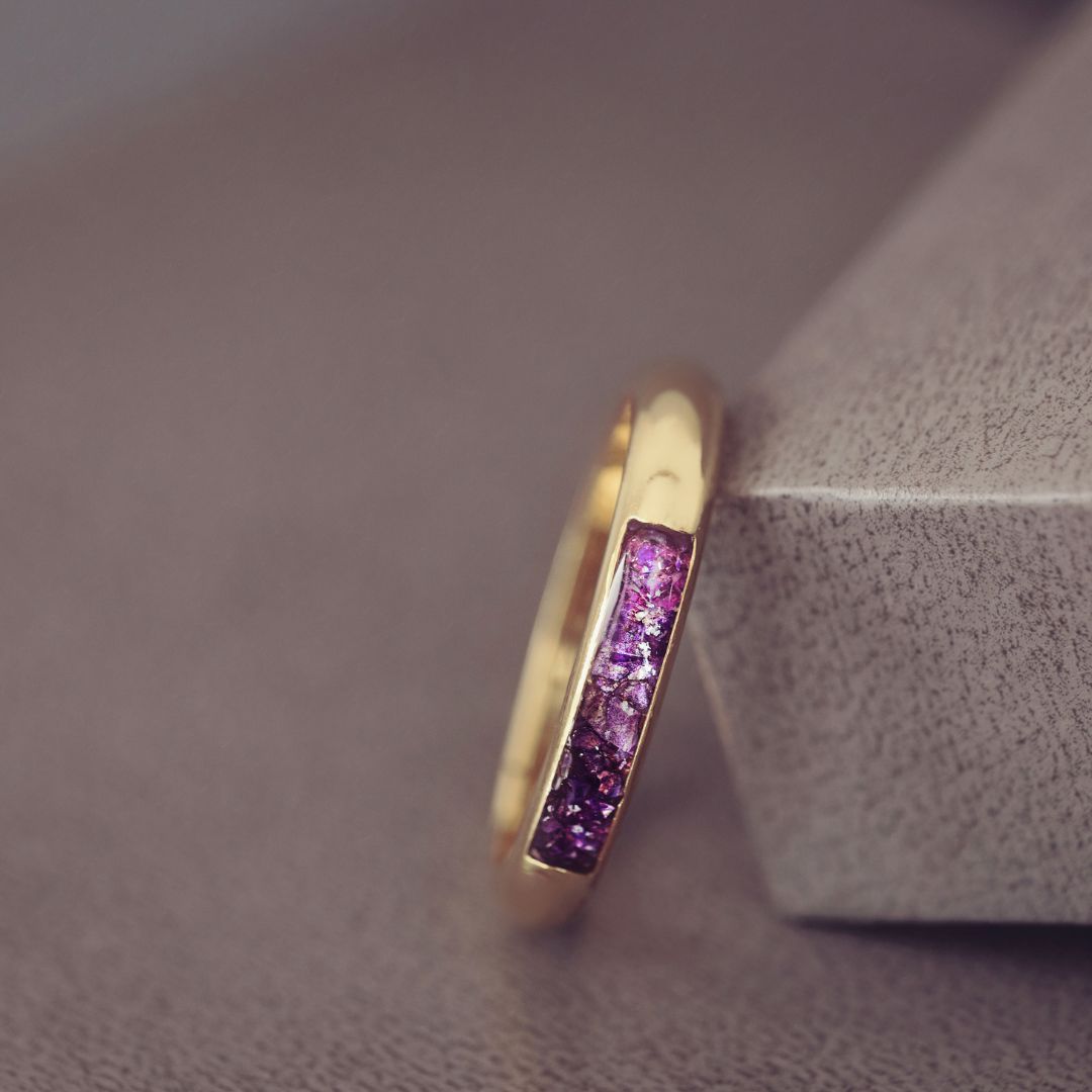 Gold ring with purple gemstones on a textured surface