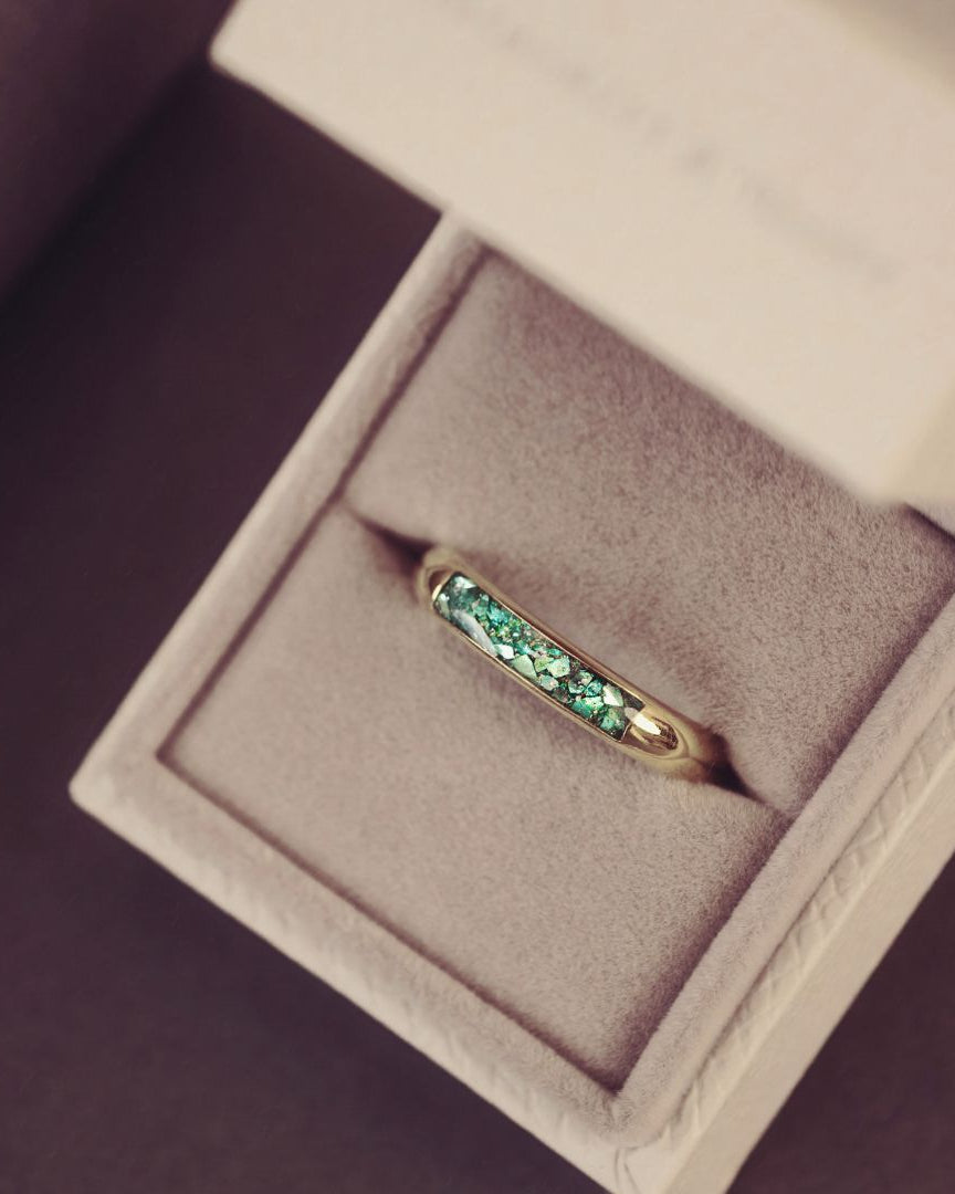 Gold ring with green gemstones in a jewelry box
