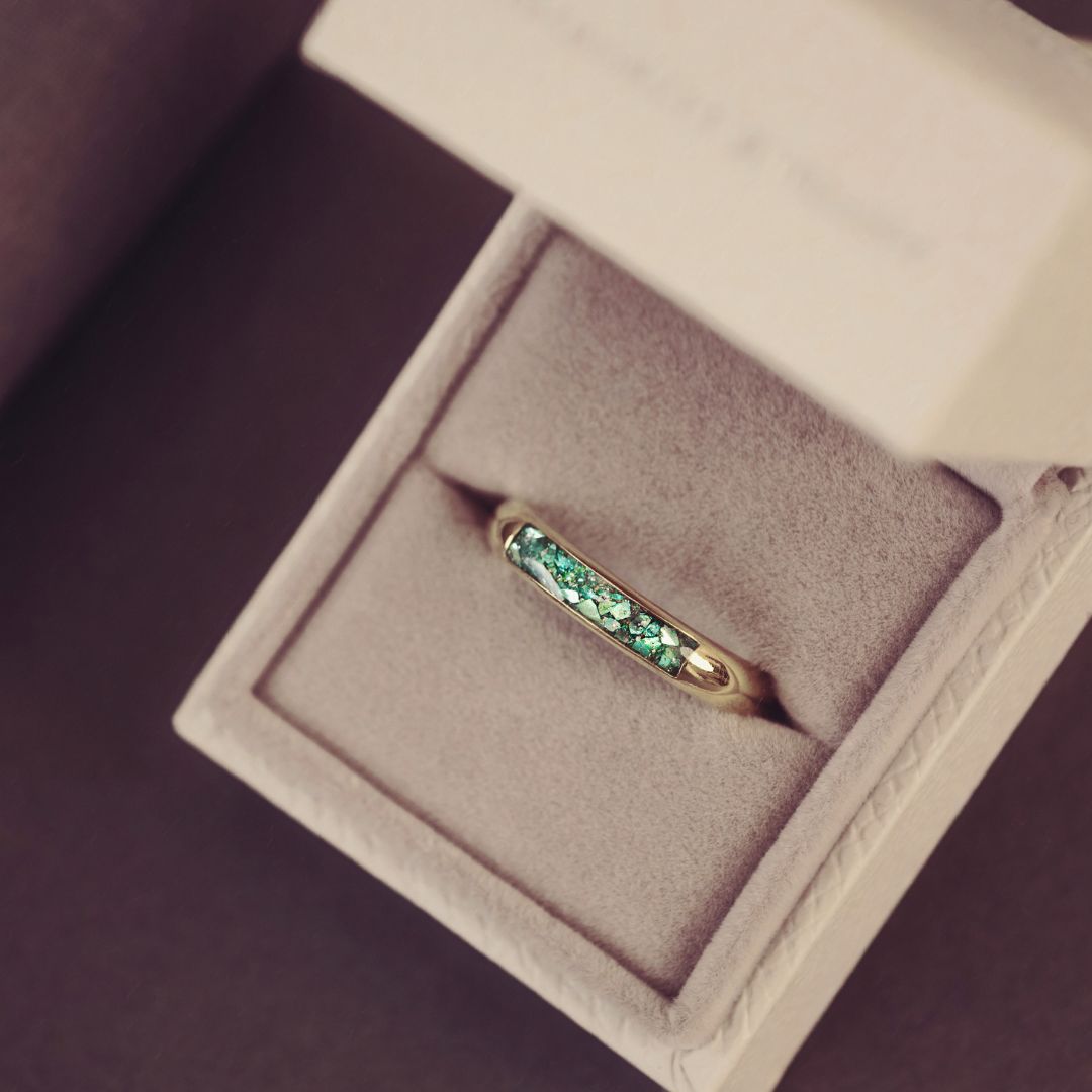 Gold ring with green gemstones in a jewelry box
