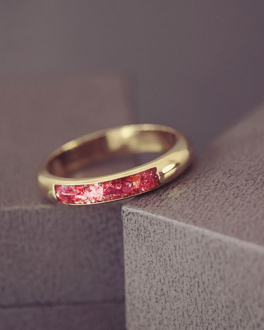 Gold ring with red gemstones on a textured surface