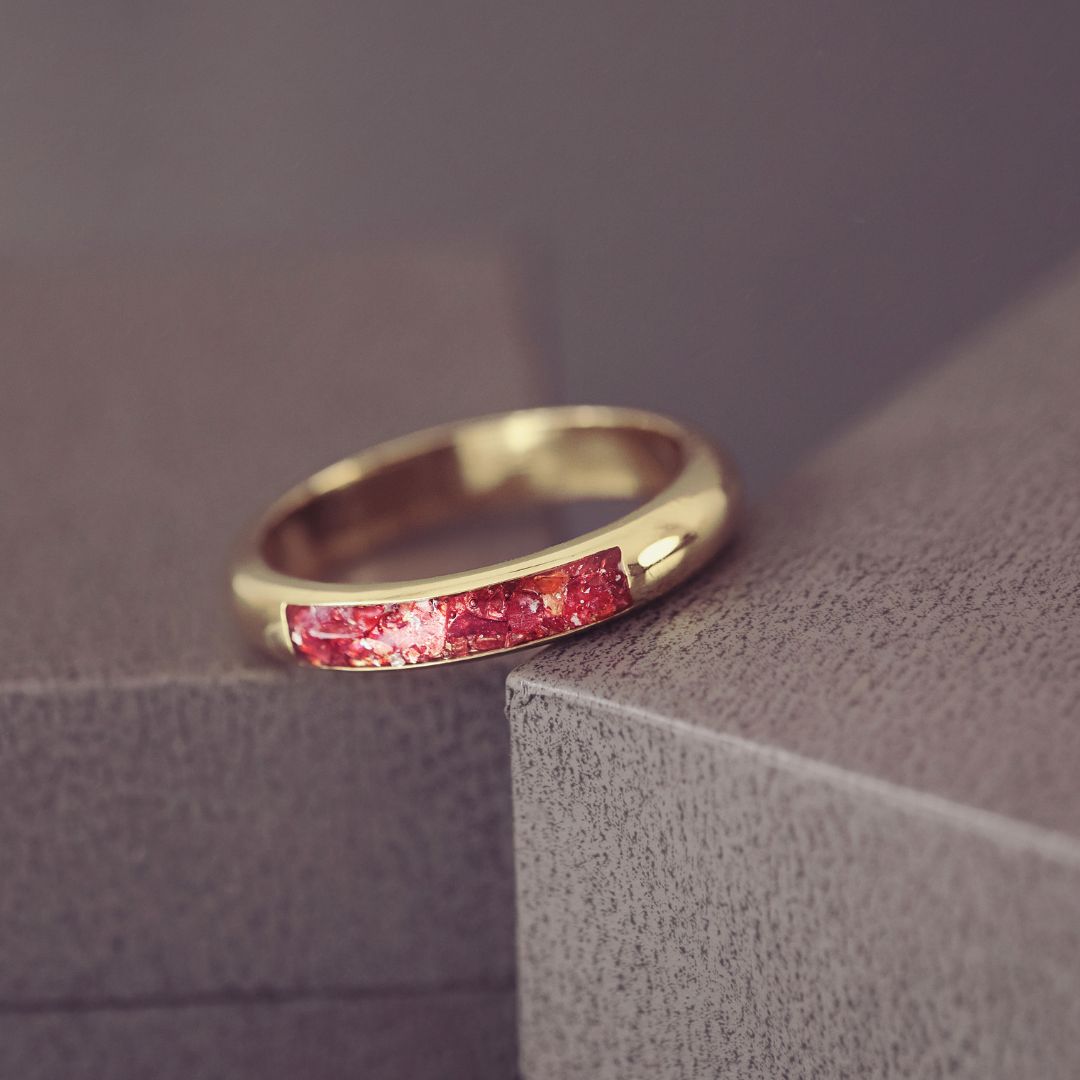Gold ring with red gemstones on a textured surface