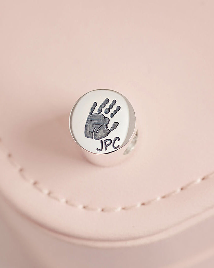 a round sterling silver charm bead, compatible with Pandora Bracelets, with a handprint and the initials JPC engraved into the front of the bead