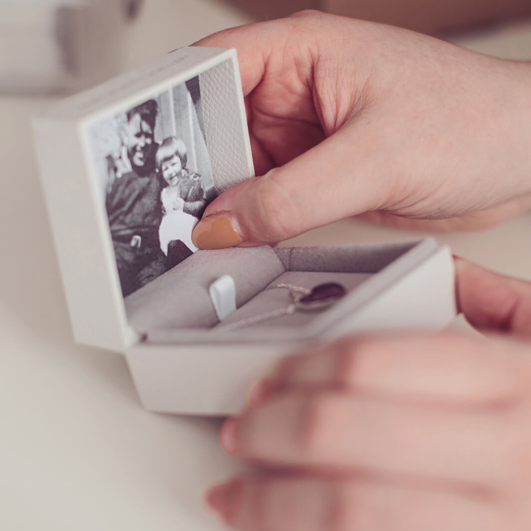 A close up of a women delicately holding a Hand on Heart Jewellery box containing a black and white photo of a loved one