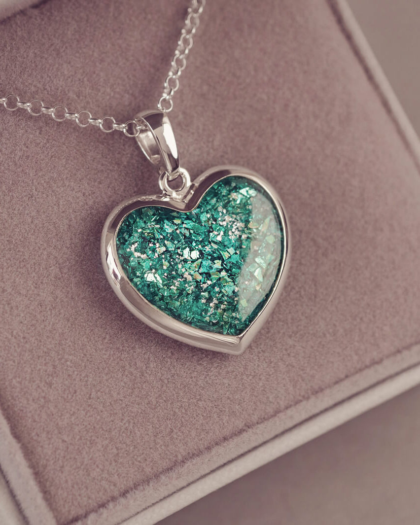Sterling silver Large Heart necklace with a central section filled with memorial ashes and green crushed crystals, displayed in a grey jewellery box