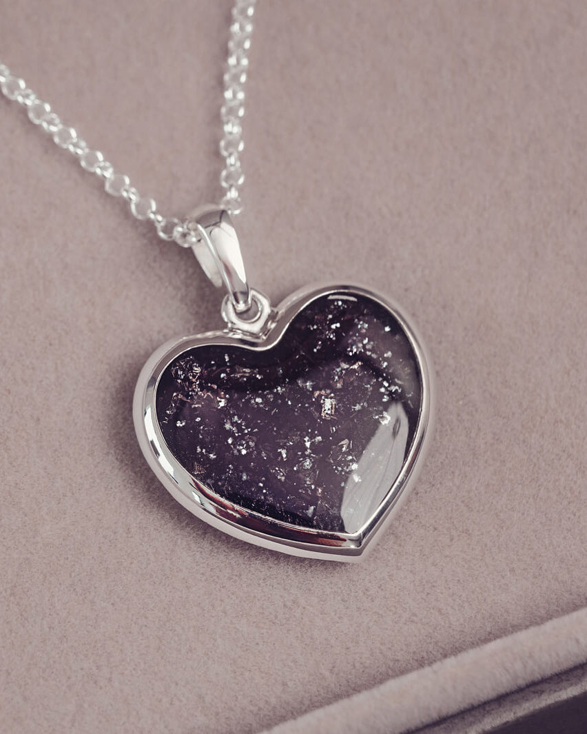 A sterling silver large heart pendant, hanging on a sterling silver belcher chain. The centre of the heart is filled with black crystal and ashes.