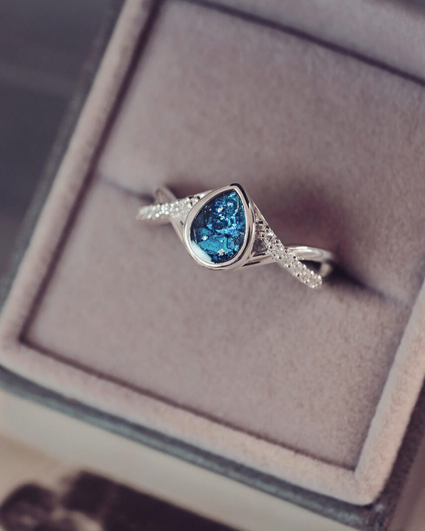 Sterling silver, peardrop shaped ring with a blue stone, created using cremation ashes and crystal