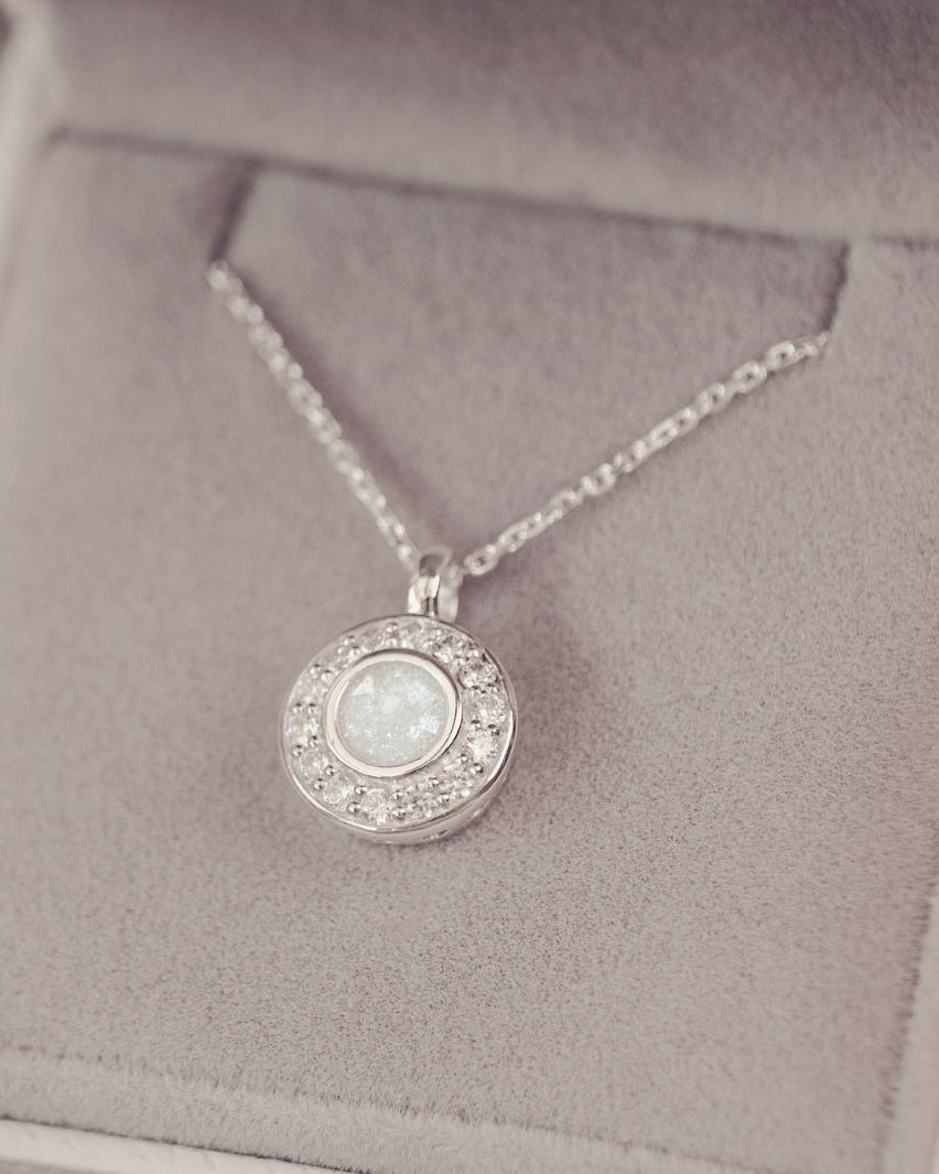 Silver necklace with a round pendant on a soft gray background