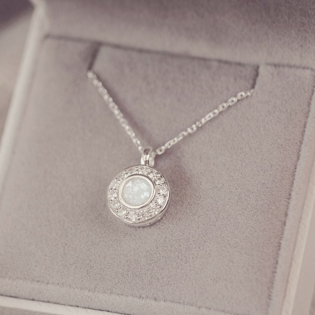 Silver necklace with a round pendant on a soft gray background