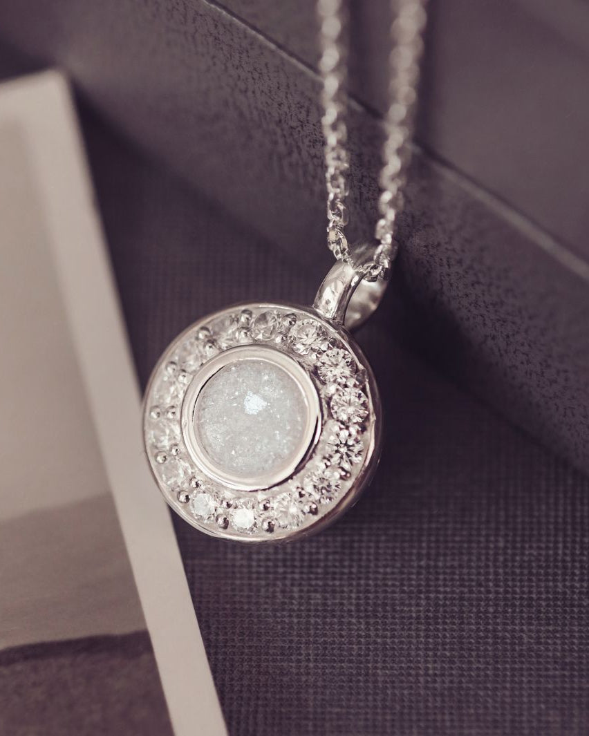 Silver necklace with a round pendant on a textured surface