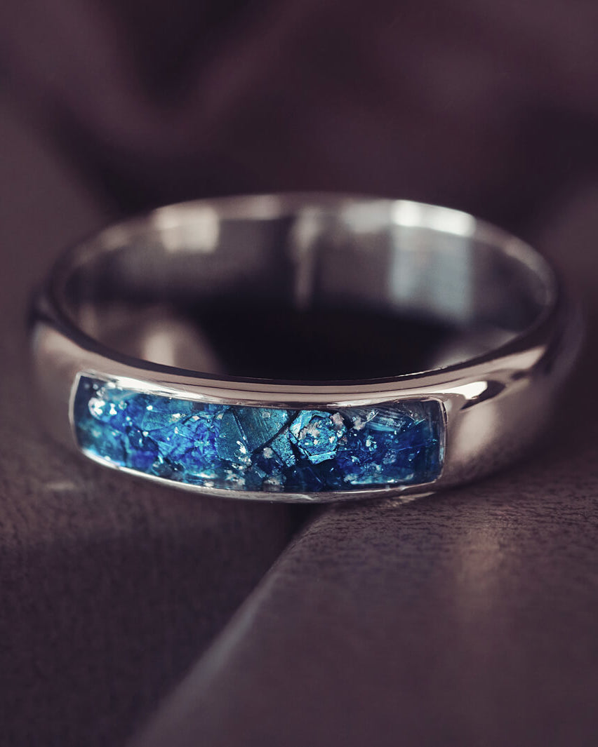 Sterling silver Mens Band Ring with a central section filled with memorial ashes and blue crushed crystals, displayed on a grey background