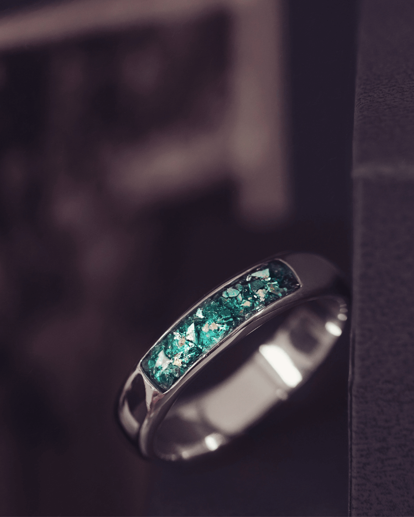 Sterling silver Mens Band Ring with a central section filled with memorial ashes and green crushed crystals, displayed on a dark grey background