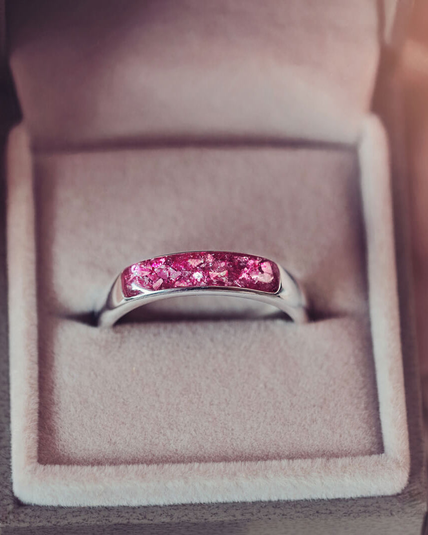 Sterling silver Mens Band Ring with a central section filled with memorial ashes and pink crushed crystals, displayed in a grey jewellery box