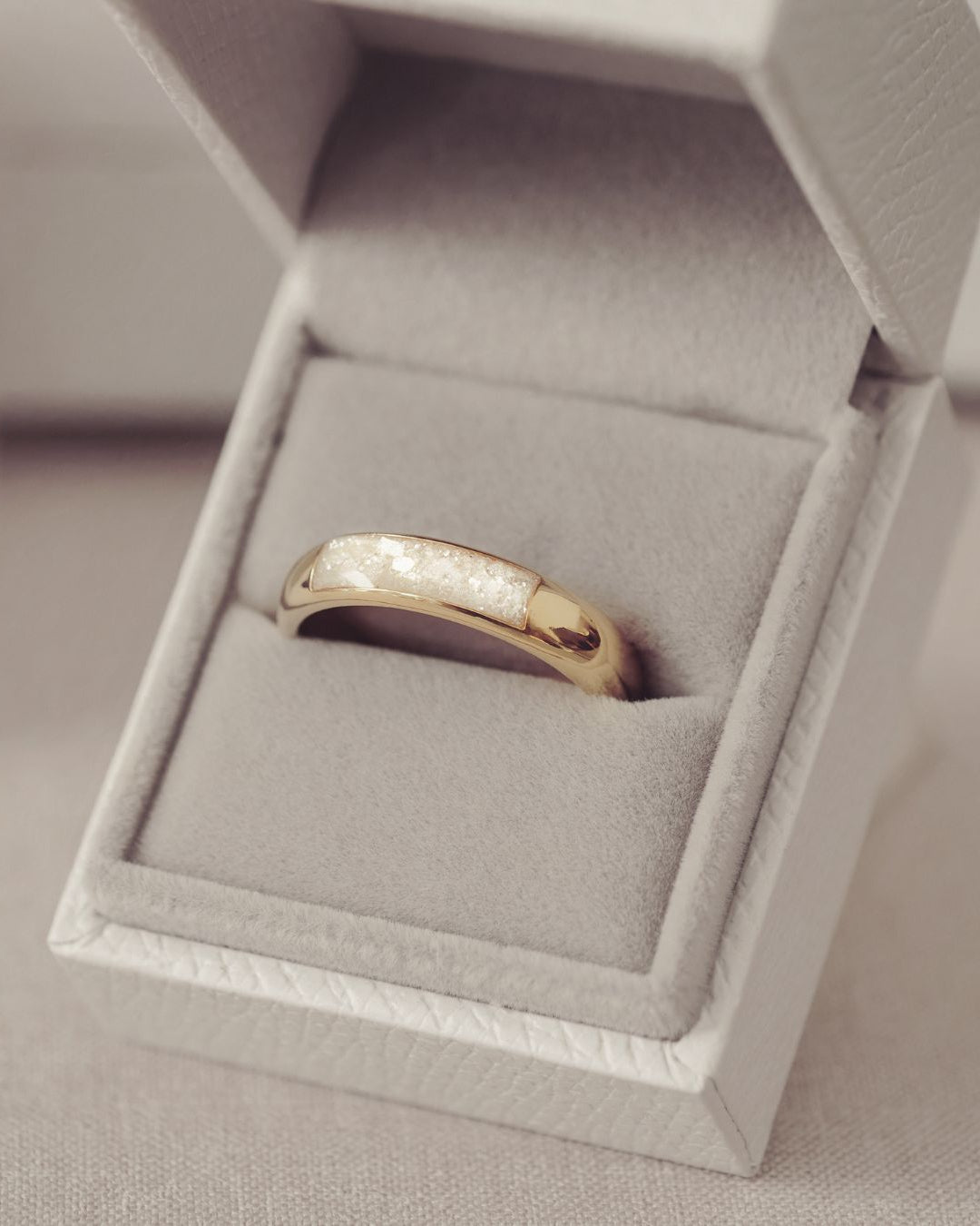 Gold ring in a gray jewelry box on a light gray background