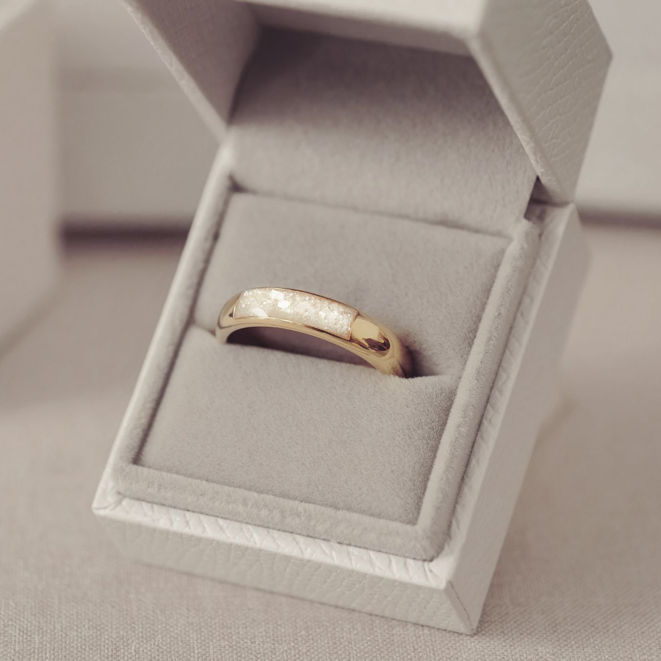 Gold ring in a gray jewelry box on a light gray background