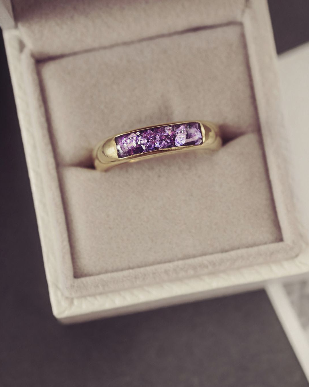 Gold ring with purple gemstones in a jewelry box