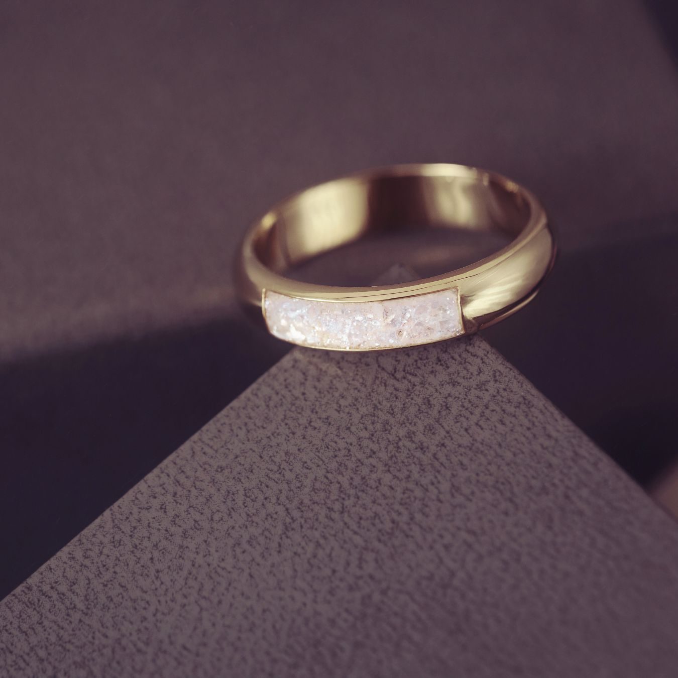 Gold ring with embedded stones on a textured purple surface