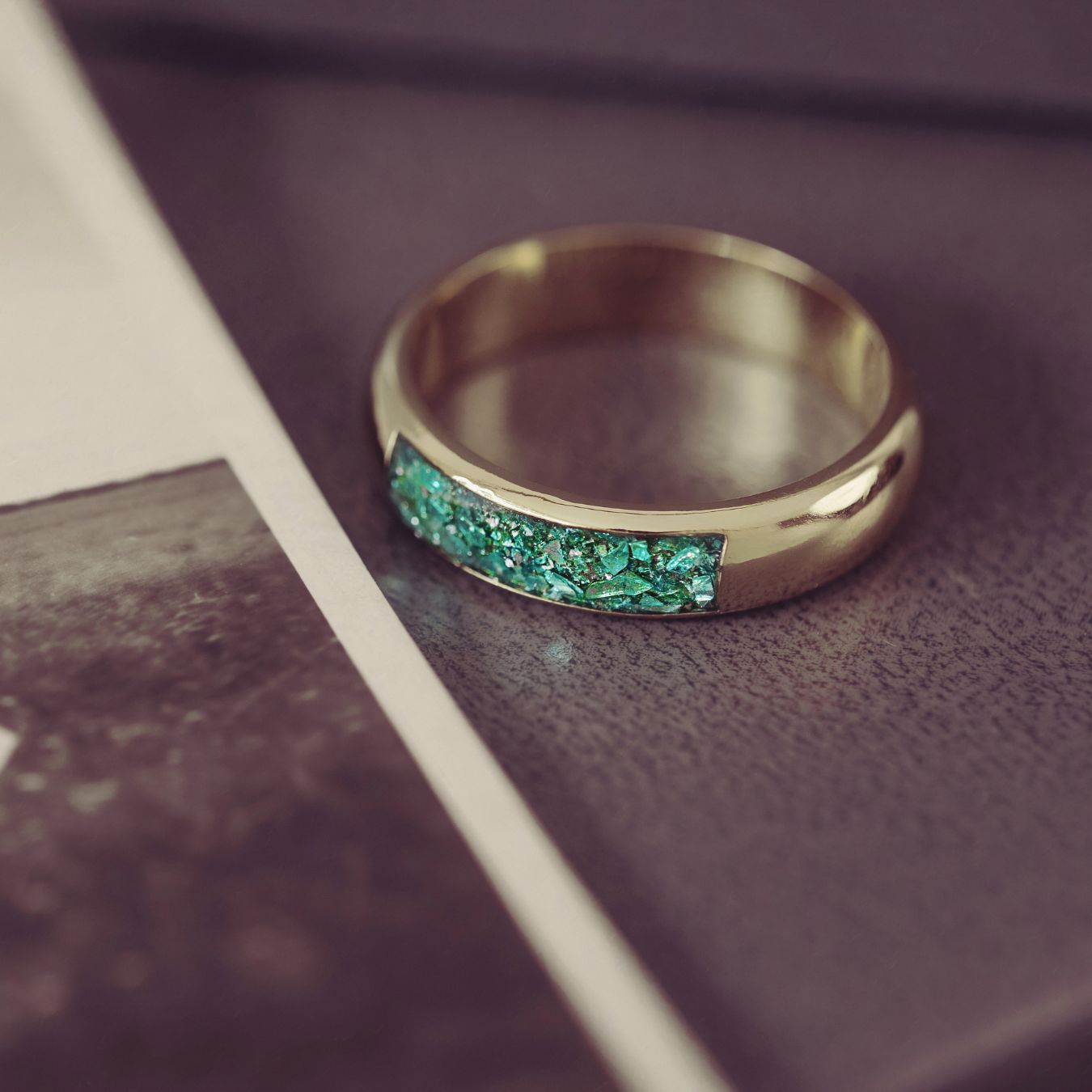 Gold ring with green gemstones on a textured surface