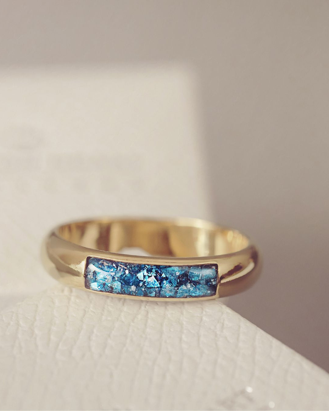 Gold ring with blue gemstone inlay on a light background