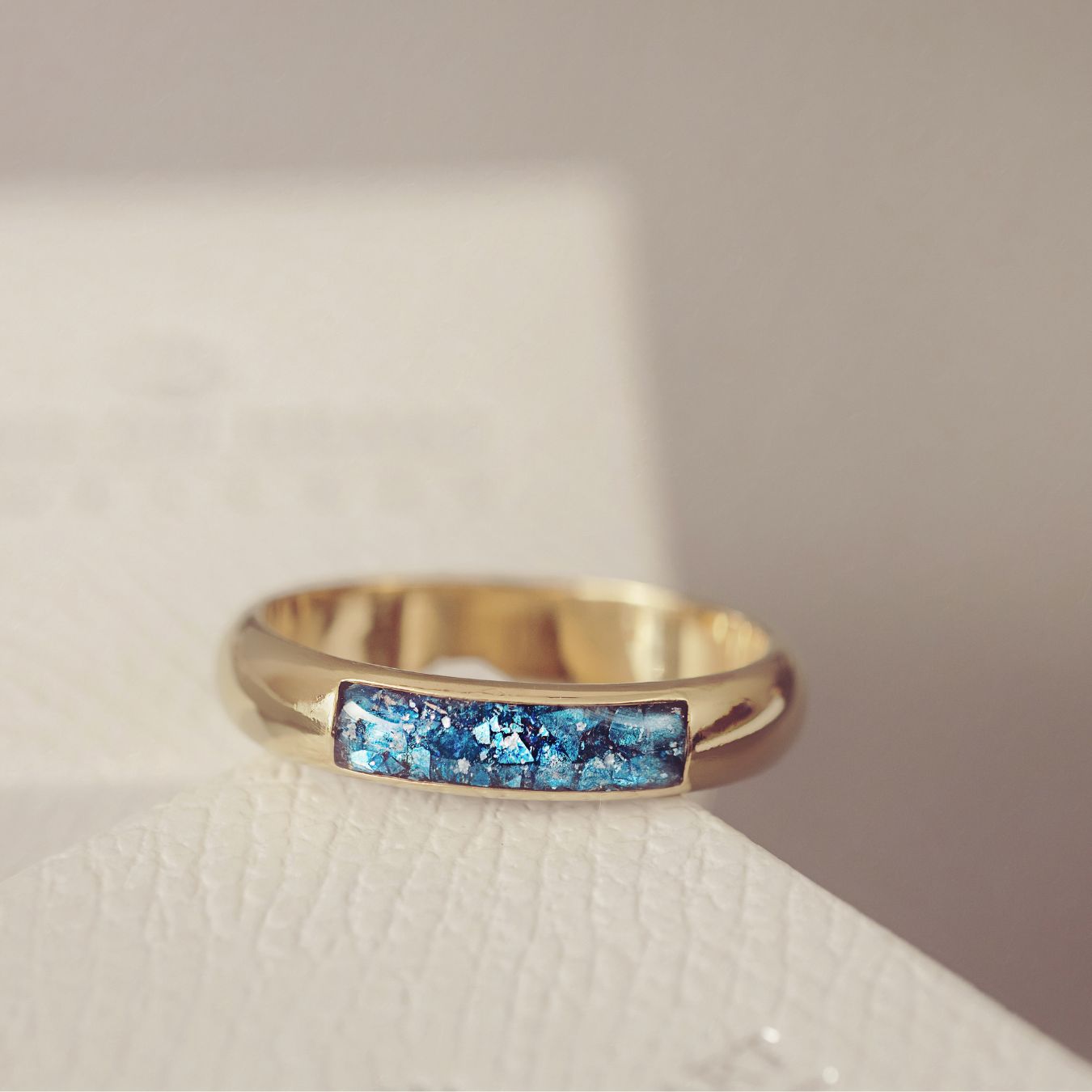 Gold ring with blue gemstone inlay on a light background