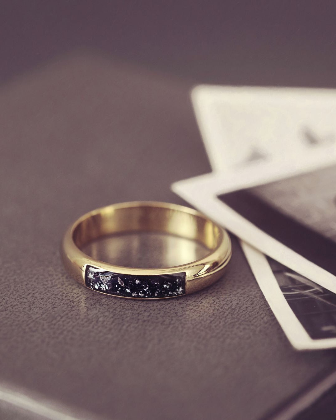 Gold ring with a black gemstone on a textured surface with playing cards.