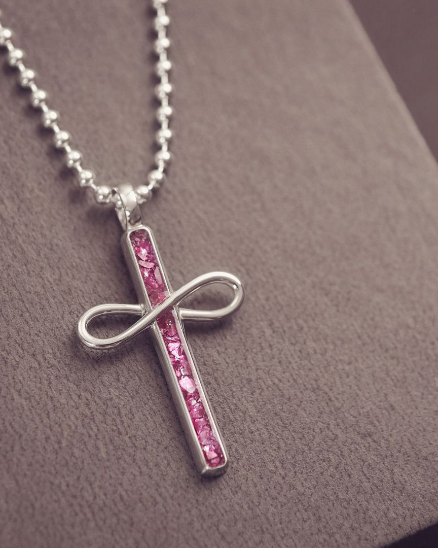 Necklace with a cross pendant featuring pink stones on a textured surface