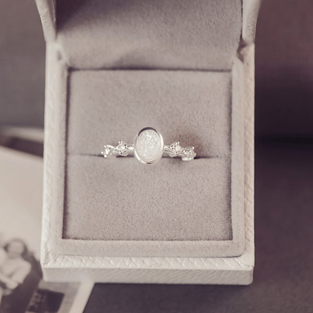 silver ring band with oval stone, created from cremation ashes & clear crystal. Sat in a jewellery box