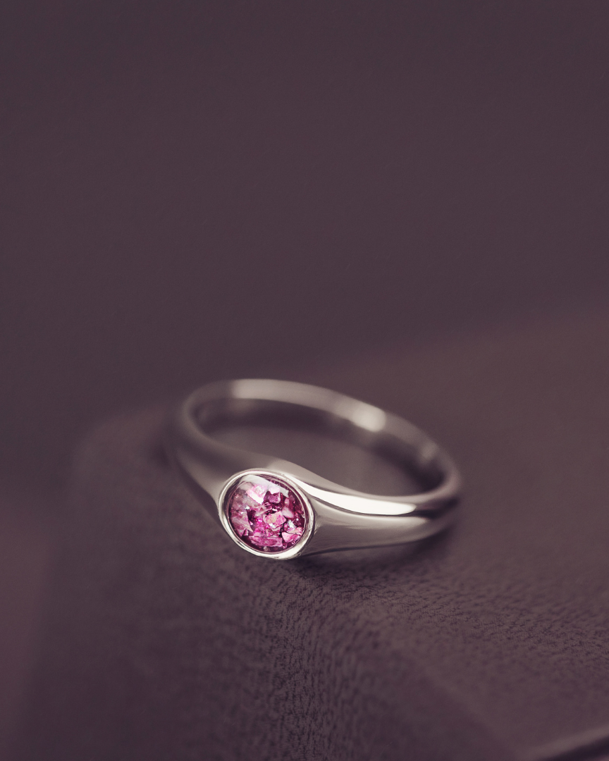 Silver ring with a pink gemstone on a dark background