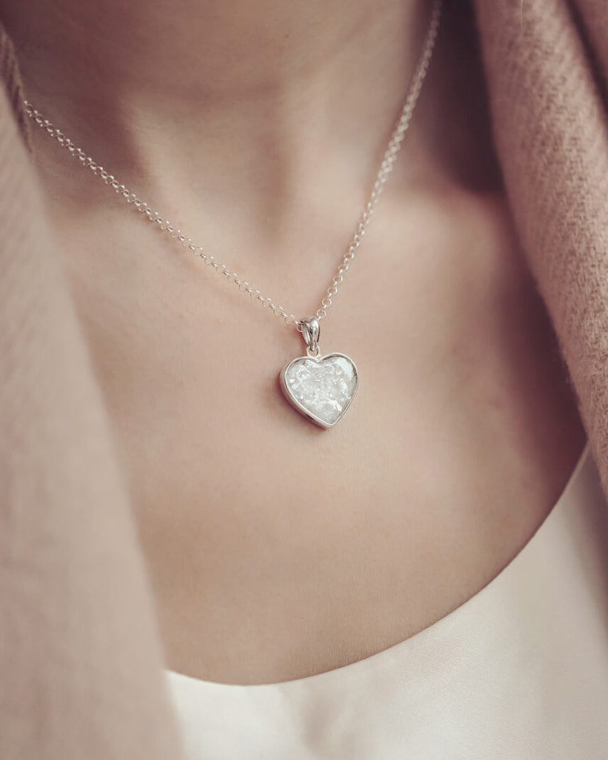 Lady wearing a Sterling silver heart necklace with a central section filled with memorial ashes and white crushed crystals
