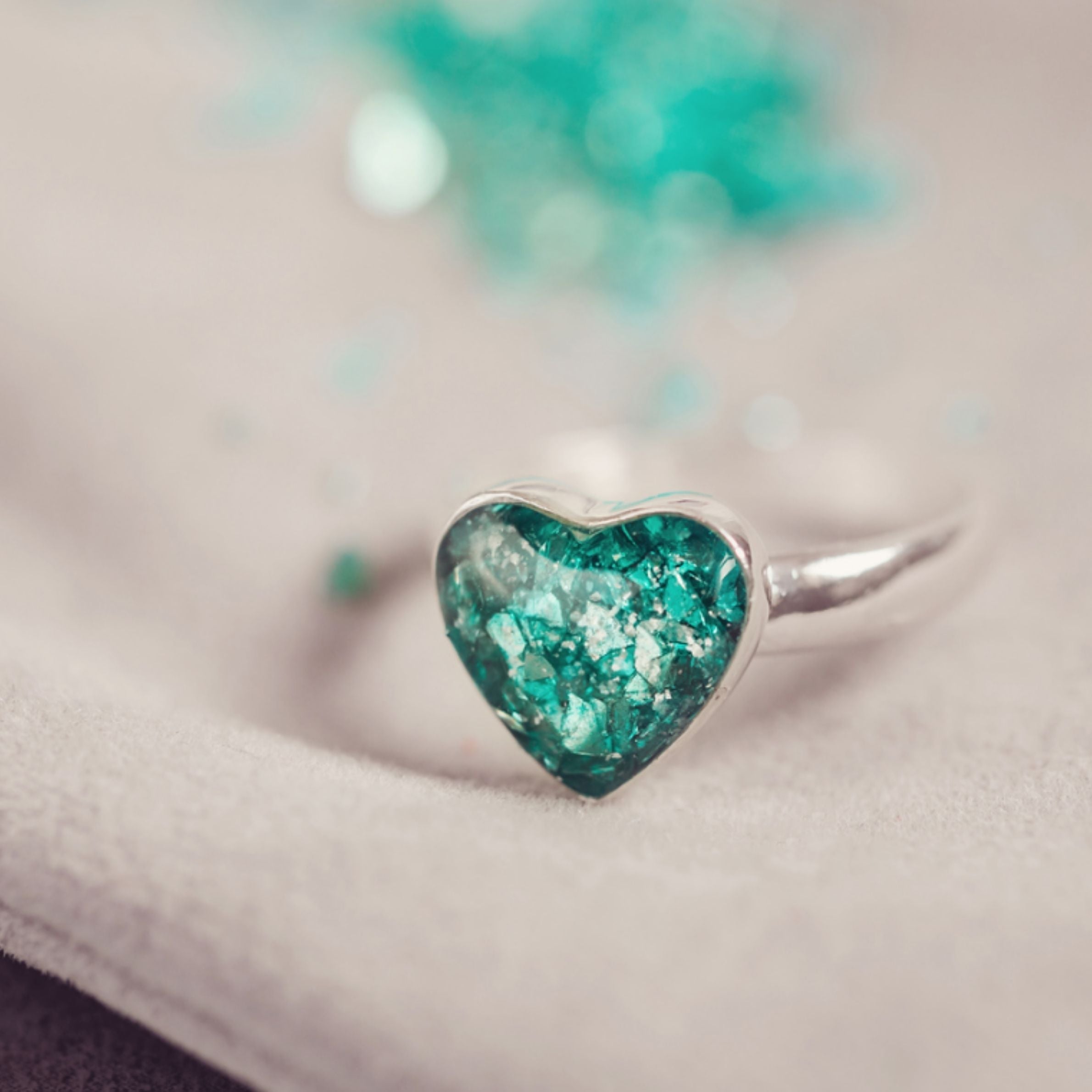 Green heart ashes ring on silver band.