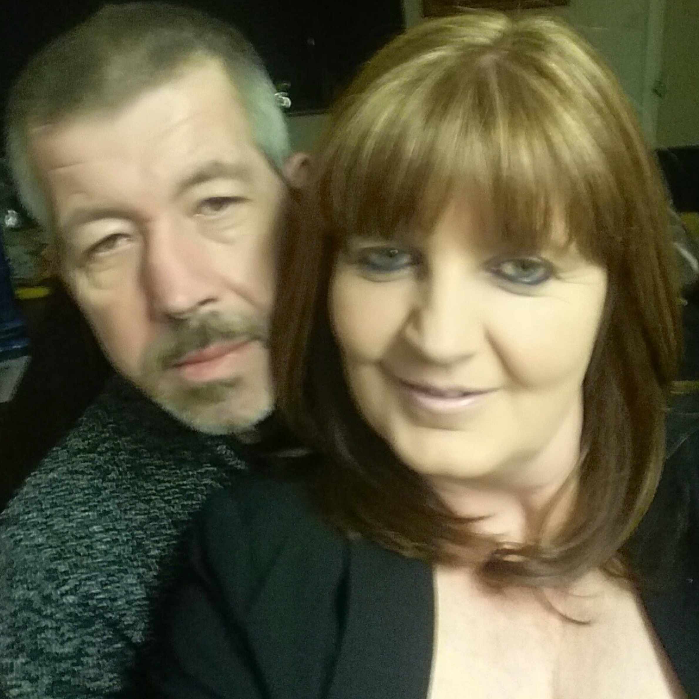 A couple taking a selfie. The man is wearing a grey jumper and the woman has a black top