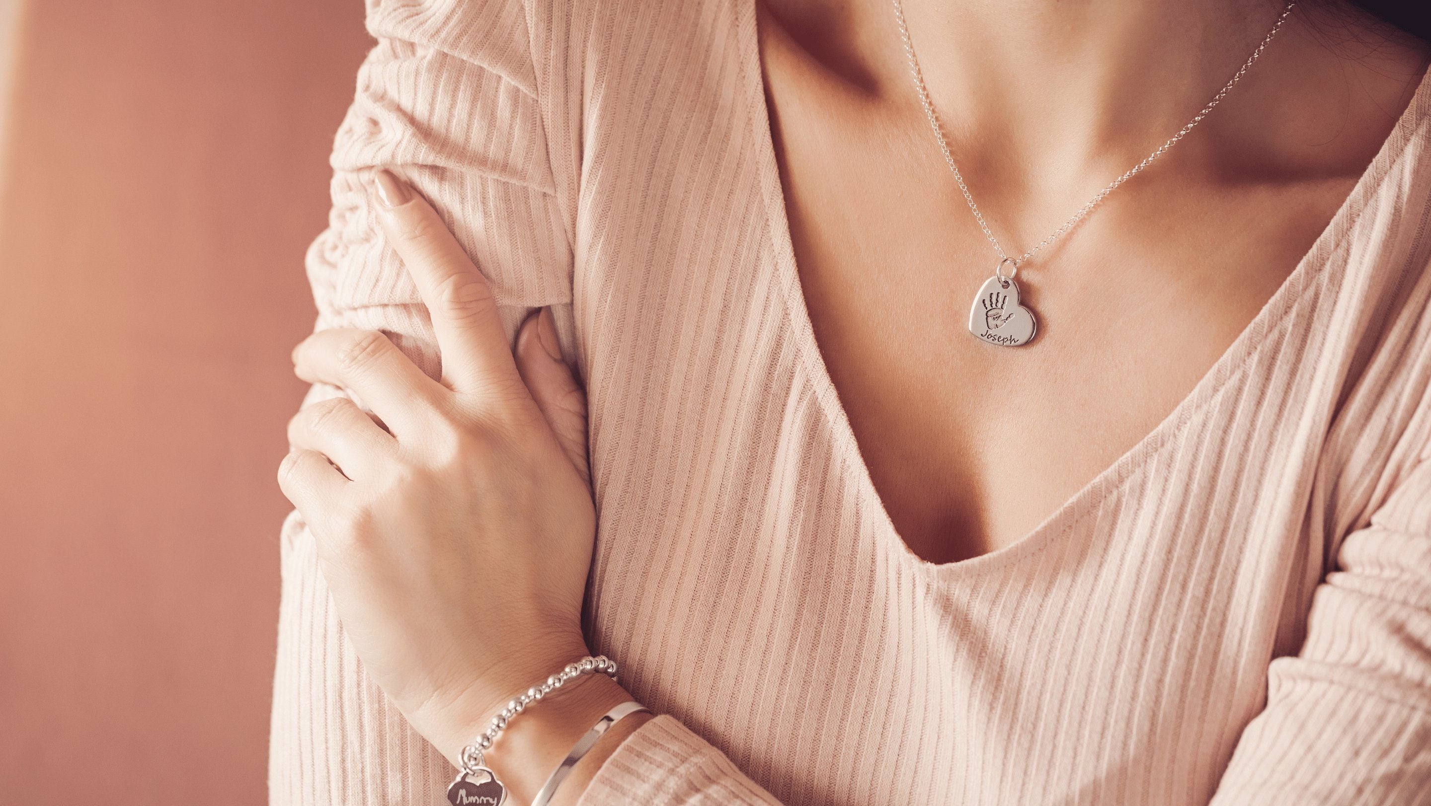 Woman wearing a silver handprint heart necklace