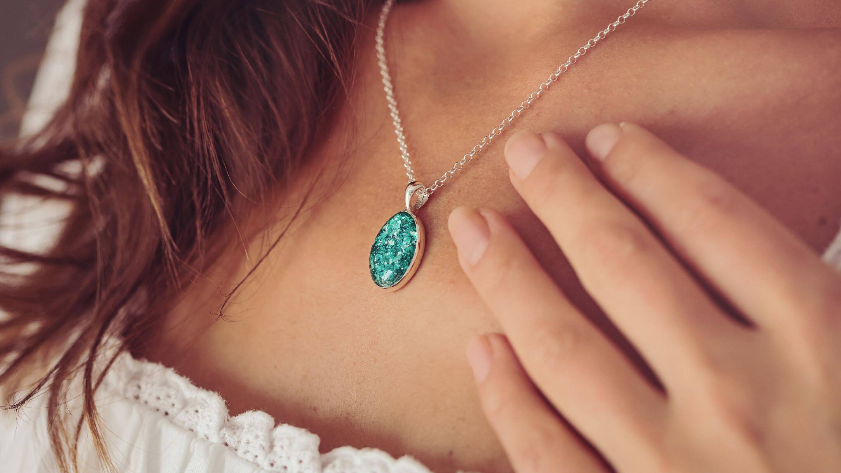 A woman wearing a Cremation Ashes Oval Necklace in green