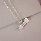 Silver bone-shaped pendant necklace with 'Bruno' engraving on a light gray background