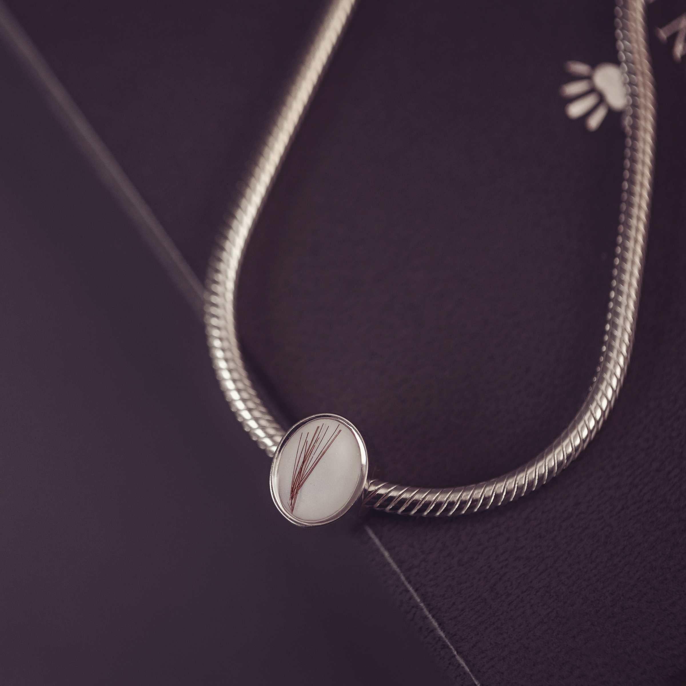 Silver thick snake chain with an oval charm on a dark background