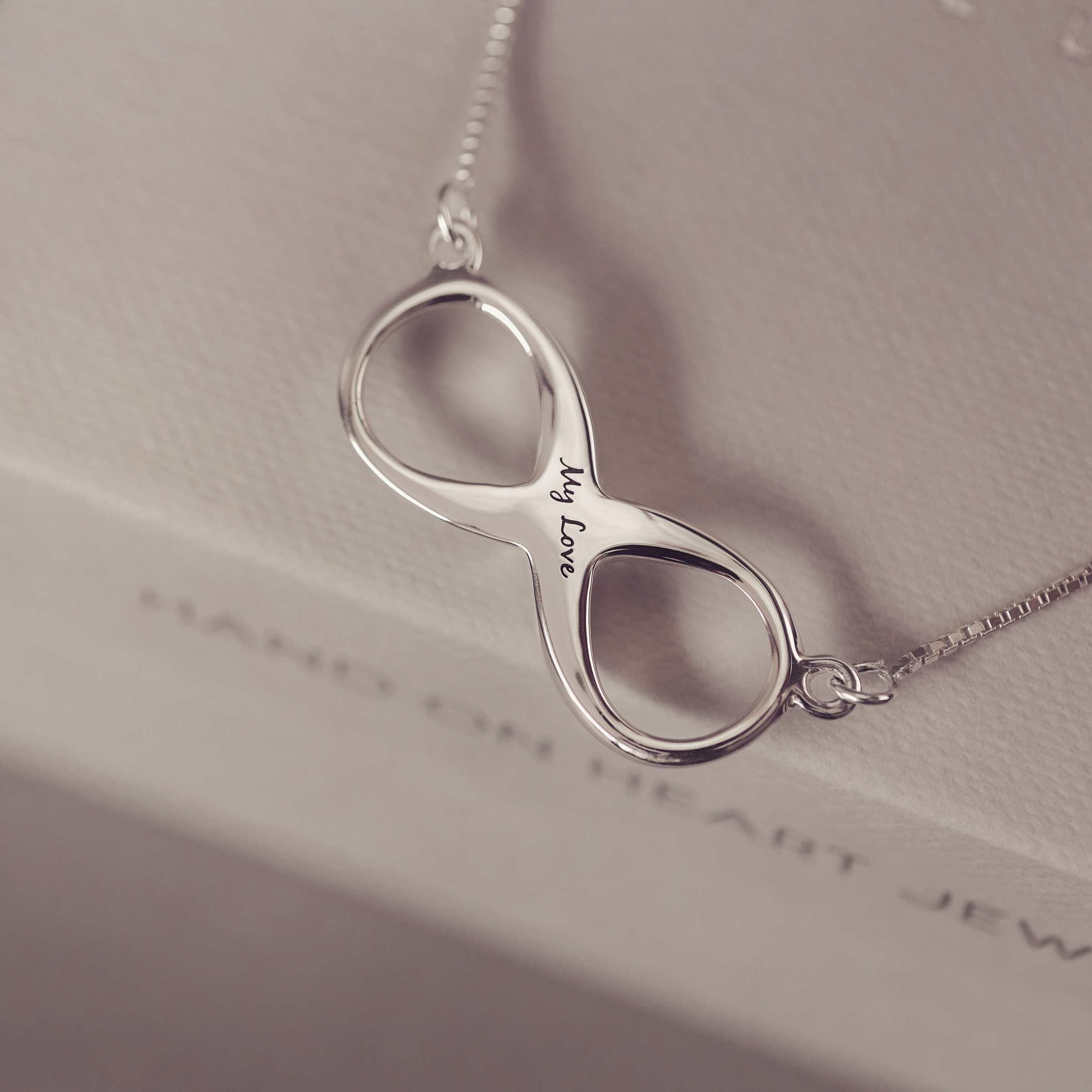 Silver infinity necklace with 'My Love' engraving on a soft background
